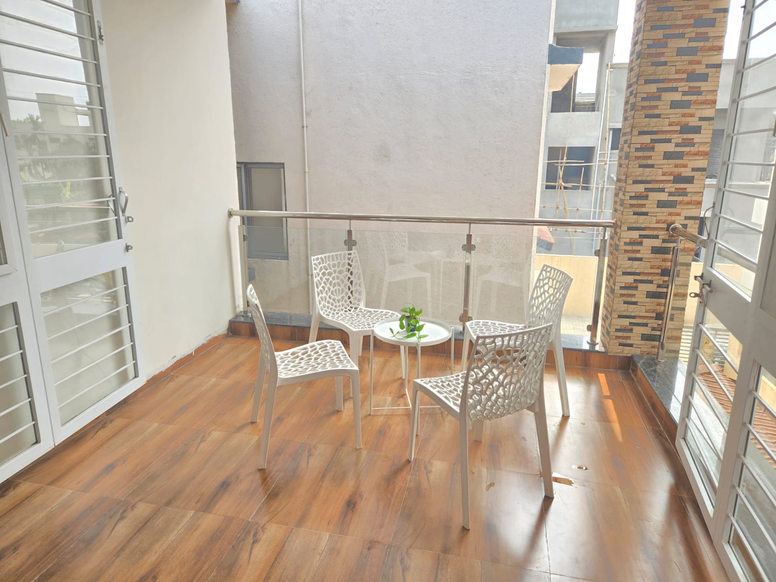 Wooden balcony with chairs and glass railing at Saanjh villa